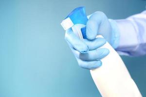 Hand in blauen Gummihandschuhen mit Sprühflasche mit Kopierraum foto