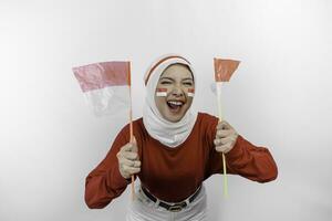 ein jung asiatisch Muslim Frau mit ein glücklich erfolgreich Ausdruck tragen rot oben und Weiß Hijab während halten Indonesiens Flagge, isoliert durch Weiß Hintergrund. Indonesiens Unabhängigkeit Tag Konzept. foto