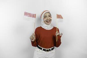 glücklich lächelnd indonesisch Muslim Frau tragen rot oben und Weiß Hijab halten Indonesiens Flagge zu feiern Indonesien Unabhängigkeit Tag. isoliert durch Weiß Hintergrund. foto