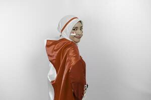 glücklich lächelnd indonesisch Muslim Frau tragen rot oben und Weiß Hijab halten Indonesiens Flagge zu feiern Indonesien Unabhängigkeit Tag. isoliert durch Weiß Hintergrund. foto