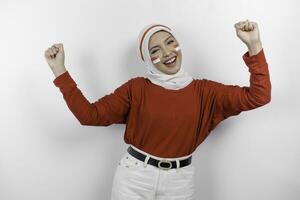 ein jung asiatisch Muslim Frau mit ein glücklich erfolgreich Ausdruck tragen rot oben und Weiß Hijab isoliert durch Weiß Hintergrund. Indonesiens Unabhängigkeit Tag Konzept. foto