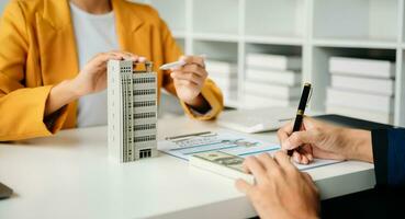 einen Vertrag unterzeichnen. kunden- und maklervertreter, mietvertrag, erfolgreiches geschäft und junges geschäft, das am schreibtisch im büro sitzt foto