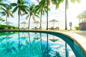 Wunderschöner Luxus-Sonnenschirm und -Stuhl um den Außenpool im Hotel und Resort mit Kokospalme bei Sonnenuntergang oder Sonnenaufgang