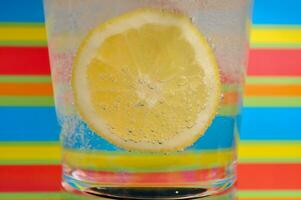 Limonade sprudelnd trinken im ein klar Glas mit bunt Hintergrund zeigen sprudelnd Luftblasen foto