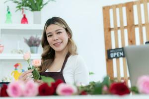 schön asiatisch Frau Florist halten Strauß von Rosen im Blume Geschäft. foto