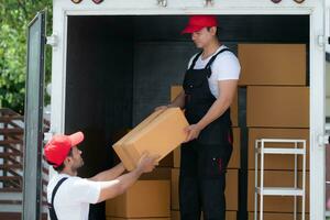 asiatisch Lieferung Mann im Uniform liefern Paket zu Kunde im zurück von LKW. foto