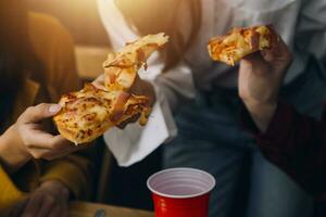 Gruppe von jung freunde Essen Pizza beim Zuhause und haben Spaß foto