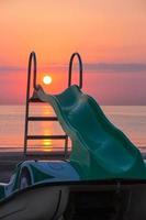 Tretboot am Strand während des erstaunlichen Sonnenaufgangs am Meer am Strand von Rivazzurra Rimini Italien foto