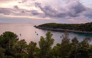 Segelboote auf dem Wasser während des dramatischen Sonnenuntergangs in der Bucht von Fetovaia, Insel Elba, Toskana, Italien foto