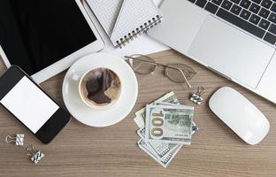 Laptop mit Büromaterial und Geld auf dem Tisch. foto