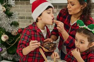 schön Mama und Kinder, bezaubernd Kinder, Sohn und Tochter Essen Zutaten, getrocknet Früchte und Nüsse während Kochen zusammen beim Zuhause Küche foto