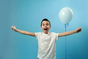 glücklich Schüler ausdrücken Glück Stehen auf Blau Hintergrund in der Nähe von ein Blau Ballon. foto