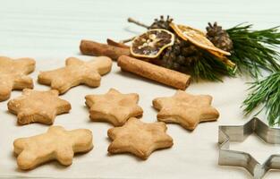 Lebkuchen Kekse wie Sterne gestalten zum Weihnachten, auf ein hölzern Oberfläche mit Kiefer Zapfen und Geäst, getrocknet Scheiben von Orange und Zimt Stöcke foto