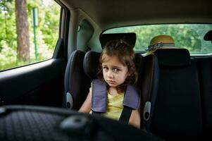 befestigt wenig Mädchen zu Kind Sicherheit Sitz Innerhalb Wagen. sicher Bewegung von Kinder im das Wagen. foto