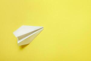 ein Weiß Papier Flugzeug isoliert auf ein Gelb Hintergrund. eben legen, oben Sicht, Kopieren Raum foto