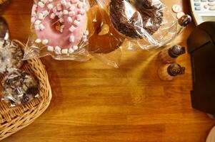 Donuts mit verschiedene Glasur und Bäckerei Produkte auf ein hölzern Oberfläche. Flatlay Komposition mit Kopieren Raum auf ein hölzern Hintergrund foto