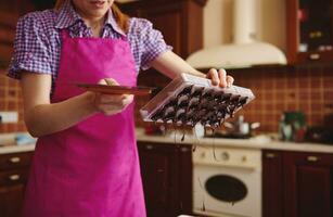 Chocolatier entfernen Überschuss Schokolade Masse von Formen auf das Marmor Tisch, zum Herstellung handgemacht Schokolade Pralinen foto