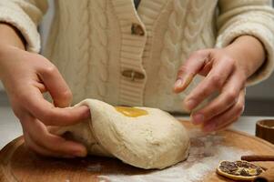 weiblich Bäcker vorbereiten Lebkuchen, Brot Teig, kneten Teig beim ein hölzern Tafel im Küche foto