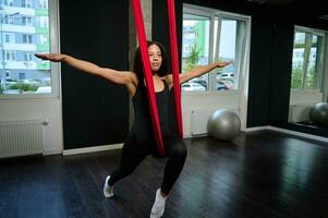 schlank Körper jung afrikanisch amerikanisch Frau üben Antenne fliegend Yoga Dehnen Übungen mit Anti Schwerkraft foto