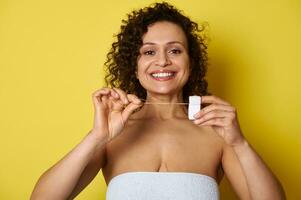 lächelnd Frau posieren zu das Kamera mit s Dental Zahnseide im ihr Hände foto