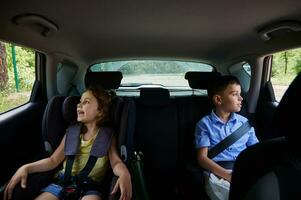 angeschnallt Kinder, Junge und Mädchen, Reisen im ein Sicherheit Booster Sitz Innerhalb das Wagen. sicher Reise mit Kinder im das Auto foto