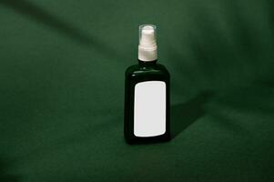 dunkel Glas Flasche mit Weiß Etikette mit kosmetisch Produkt, Schuss mit Schatten von ein Palme Blatt fallen auf Grün Hintergrund foto