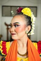 schön Gesicht von ein traditionell indonesisch Tänzer tragen Blumen und charmant bilden Vor durchführen foto