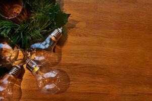 eben legen Komposition mit Ornament von transparent Lampen auf ein Kiefer Ast Lügen auf ein hölzern Tafel mit Kopieren Raum foto