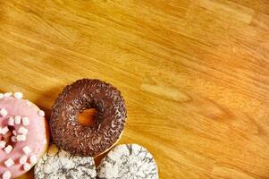 sortiert Donuts mit Sträusel auf hölzern Oberfläche. Hintergrund mit Kopieren Raum. foto