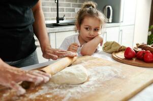 Mama und Tochter Koch Pizza zusammen. Nahansicht von süß Mädchen Aufpassen ihr Mutter rollen aus das Teig mit ein hölzern rollen Stift foto