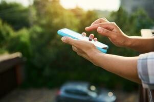 Nahansicht von Frau Hände halten Handy, Mobiltelefon Telefon gegen Sonnenlicht Hintergrund foto