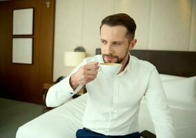erfolgreich Mitte alt europäisch Geschäftsmann im Geschäft beiläufig Outfit Trinken Kaffee im Hotel Wohnung während Geschäft Reise. frisch gebraut Kaffee zum das perfekt Start zu das Tag foto