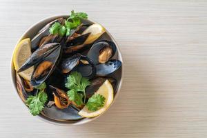 Muscheln mit Kräutern in einer Schüssel mit Zitrone foto