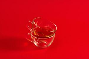 zwei transparent Glas Tassen auf ein rot Oberfläche. Schuss mit Sanft Schatten auf rot Hintergrund mit Kopieren Raum foto
