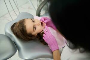 Baby Mädchen, bezaubernd Kind im Zahnarzt Stuhl beim regulär medizinisch Untersuchung während Kinderarzt Zahnarzt besuchen. Oral Pflege, Dental Hygiene, Gesundheit Pflege und medizinisch Inhalt.gesund schön Zähne Konzept foto