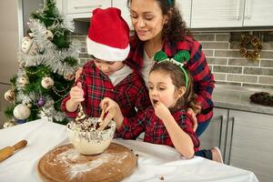 schön heiter atemberaubend Erfreut jung spanisch Mutter und ihr bezaubernd Kinder, Sohn und Tochter Kochen zusammen im das Zuhause Küche während Weihnachten Ferien foto