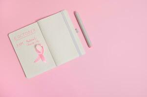 eben legen Komposition von ein Rosa Band, auf geöffnet Notizblock mit Inschriften erinnern von ein medizinisch Untersuchung. Oktober 1, Welt Brust Krebs Tag, Damen Gesundheit Pflege und medizinisch Konzept. foto