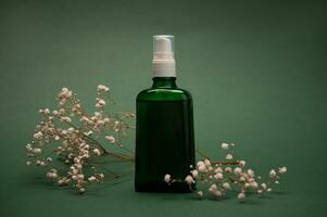 stilvoll minimalistisch Attrappe, Lehrmodell, Simulation Flasche mit kosmetisch Massage Öl auf ein Grün Hintergrund mit Gypsophila Blumen. Kopieren Anzeige Raum foto