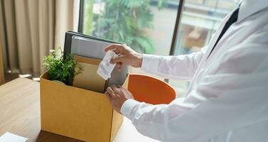 Verlassen Job Geschäft Mann Senden Rücktritt Brief und Verpackung Zeug zurücktreten drücken oder Tragen Geschäft Karton Box im Büro. Veränderung von Job oder gefeuert von Unternehmen. foto