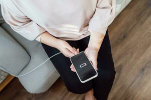 Frau Hände Laden Handy, Mobiltelefon Telefon Batterie mit niedrig Batterie. Einstecken ein Ladegerät im ein Clever Telefon mit Energie Bank Powerbank Leistung Ladegerät modern Lebensstil Energie Technologie Konzept foto