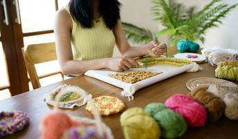 schlagen Nadel. asiatisch Frau Herstellung handgemacht Hobby Stricken im Studio Werkstatt. Designer Arbeitsplatz handgemacht Kunst Projekt DIY Stickerei Konzept. foto