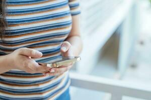 Frau SMS Überprüfung Sozial Medien halten Smartphone beim Zuhause Konversation mit Freund oder Freund foto