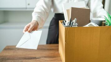 Geschäft Frau Senden Rücktritt Brief und Verpackung Zeug zurücktreten drücken oder Tragen Geschäft Karton Box durch Schreibtisch im Büro. Veränderung von Job oder gefeuert von Unternehmen foto