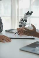Fachmann Labor. tolle langhaarig medizinisch Arbeiter tragen Uniform während mit Mikroskop während Forschung foto