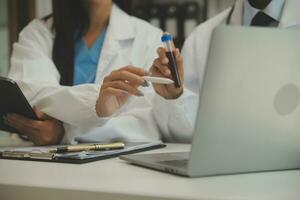 Selbstbewusster Arzt, der eine Tablettenflasche hält und schreibt, während er mit einem älteren Patienten spricht und seine Medikamente im Büroraum überprüft. foto