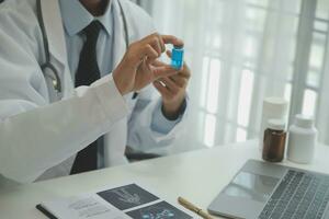 Selbstbewusster Arzt, der eine Tablettenflasche hält und schreibt, während er mit einem älteren Patienten spricht und seine Medikamente im Büroraum überprüft. foto