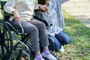 Familie Beziehung asiatisch Senior Frau im Rollstuhl mit glücklich Tochter halten Pflegekraft zum ein Hand während Ausgaben Zeit zusammen foto