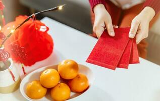 asiatisch Frau geben rot Briefumschlag zum Mond- Neu Jahr Feierlichkeiten. Hand halt rot Paket foto