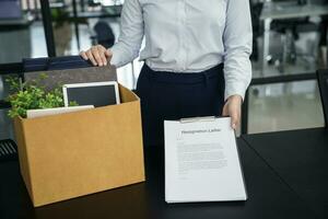 Geschäft Frau Senden Rücktritt Brief zu Boss und halten Zeug zurücktreten drücken oder Tragen Karton Box durch Schreibtisch im Büro foto