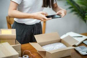 Geschäft von Zuhause asiatisch Frau vorbereiten Paket Lieferung Box Versand zum Einkaufen online. jung Start oben klein Geschäft Inhaber beim Zuhause online bestellen foto